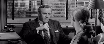 Movie still from “The Three Faces of Eve” (1957), directed by Nunnally Johnson – An older man wearing a suit and tie talking to a younger man; Medium shot, Over the shoulder angle