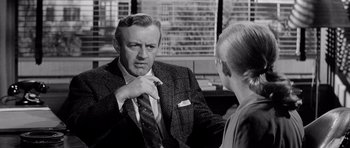 Movie still from “The Three Faces of Eve” (1957), directed by Nunnally Johnson – An older man in a suit talking to an older woman in a suit; Close Up shot, Over the shoulder angle