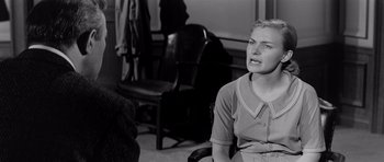 Movie still from “The Three Faces of Eve” (1957), directed by Nunnally Johnson – A woman sitting in a chair in front of a chair; Medium shot, Over the shoulder angle