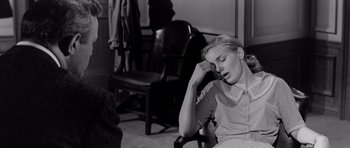 Movie still from “The Three Faces of Eve” (1957), directed by Nunnally Johnson – A woman sitting in a chair with her head resting on her hand; Medium shot, High angle