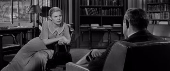 Movie still from “The Three Faces of Eve” (1957), directed by Nunnally Johnson – A black and white photo of a woman sitting in a chair; Medium shot, Over the shoulder angle