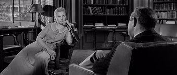 Movie still from “The Three Faces of Eve” (1957), directed by Nunnally Johnson – A black and white photo of a woman sitting in a chair; Medium shot, Over the shoulder angle