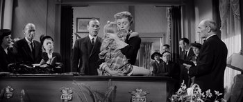 Movie still from “The Three Faces of Eve” (1957), directed by Nunnally Johnson – An old black and white photo of a woman hugging a young girl; Medium shot, Low angle