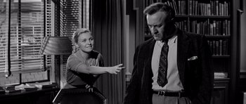 Movie still from “The Three Faces of Eve” (1957), directed by Nunnally Johnson – A woman pointing at a man in a suit; Medium shot, Over the shoulder angle