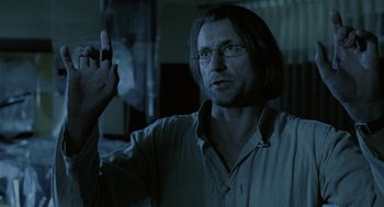 Movie still from “The Ugly Swans” (2006), directed by Konstantin Lopushanskiy – A man in a white shirt is holding his hand up; Close Up shot, Over the shoulder angle