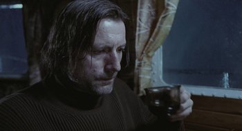 Movie still from “The Ugly Swans” (2006), directed by Konstantin Lopushanskiy – A person holding a cup of coffee; Close Up shot, Low angle
