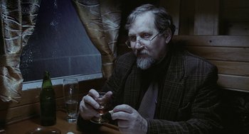 Movie still from “The Ugly Swans” (2006), directed by Konstantin Lopushanskiy – An older man sitting at a table with a glass of wine; Close Up shot, High angle