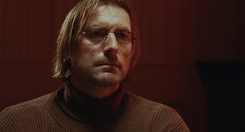 Movie still from “The Ugly Swans” (2006), directed by Konstantin Lopushanskiy – A person wearing glasses and a sweater; Close Up shot, Low angle