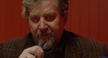 Movie still from “The Ugly Swans” (2006), directed by Konstantin Lopushanskiy – An older man with a beard holding a pair of scissors; Close Up shot, Over the shoulder angle