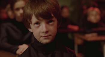 Movie still from “The Ugly Swans” (2006), directed by Konstantin Lopushanskiy – A young boy wearing a black shirt and looking at the camera; Close Up shot, Over the shoulder angle