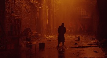 Movie still from “The Ugly Swans” (2006), directed by Konstantin Lopushanskiy – A man standing in the middle of an alley; Wide shot, Over the shoulder angle