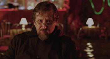 Movie still from “The Ugly Swans” (2006), directed by Konstantin Lopushanskiy – A person wearing glasses and a jacket; Close Up shot, Over the shoulder angle