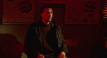 Movie still from “The Ugly Swans” (2006), directed by Konstantin Lopushanskiy – A man sitting in a chair in a dark room; Medium shot, Low angle