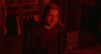 Movie still from “The Ugly Swans” (2006), directed by Konstantin Lopushanskiy – A man with long red hair and a black shirt; Close Up shot, Low angle