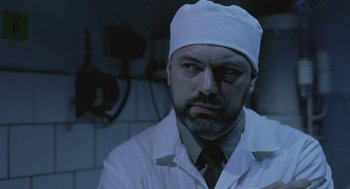 Movie still from “The Ugly Swans” (2006), directed by Konstantin Lopushanskiy – A man in a white lab coat wearing a white hat; Close Up shot, Low angle