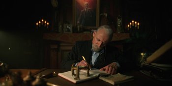 Movie still from “The Umbrella Academy” (2019), created by Steve Blackman – An older man writing on a book at a table; Medium shot, Low angle