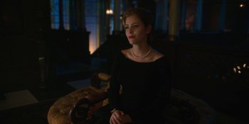 Movie still from “The Umbrella Academy” (2019), created by Steve Blackman – A woman sitting on a couch in a dark room; Medium shot, Over the shoulder angle