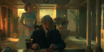 Movie still from “The Umbrella Academy” (2019), created by Steve Blackman – An older man sitting at a table in front of a woman; Medium shot, Low angle