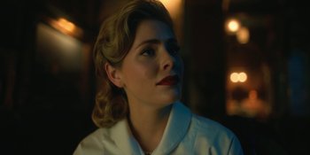 Movie still from “The Umbrella Academy” (2019), created by Steve Blackman – A woman in a white shirt and red lipstick looking to her left; Close Up shot, Low angle