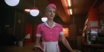 Movie still from “The Umbrella Academy” (2019), created by Steve Blackman – A woman in a pink uniform holding a wii controller; Medium shot, Low angle