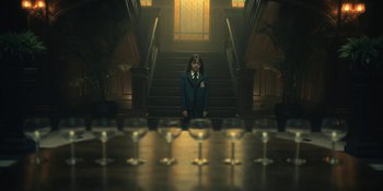 Movie still from “The Umbrella Academy” (2019), created by Steve Blackman – A little girl standing on the stairs in a room; Wide shot, Low angle