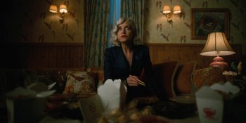 Movie still from “The Umbrella Academy” (2019), created by Steve Blackman – A woman sitting on a couch in a living room holding chopsticks; Medium shot, Low angle