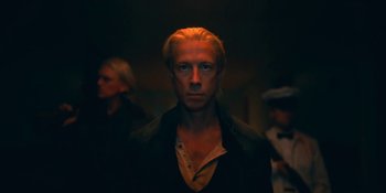 Movie still from “The Umbrella Academy” (2019), created by Steve Blackman – A man with blonde hair is standing in a dark room; Close Up shot, Low angle