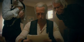 Movie still from “The Umbrella Academy” (2019), created by Steve Blackman – A man sitting in front of a sheet of paper; Medium shot, Over the shoulder angle