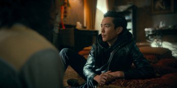 Movie still from “The Umbrella Academy” (2019), created by Steve Blackman – A man sitting on the ground in front of a television; Medium shot, Over the shoulder angle