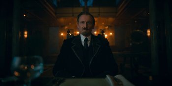 Movie still from “The Umbrella Academy” (2019), created by Steve Blackman – A man with a mustache wearing a suit and tie; Medium shot, Low angle