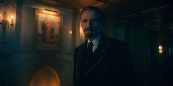Movie still from “The Umbrella Academy” (2019), created by Steve Blackman – A man in a suit and tie standing in a room; Medium shot, Low angle