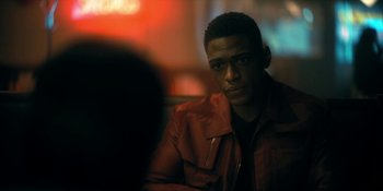 Movie still from “The Umbrella Academy” (2019), created by Steve Blackman – A man sitting in front of a camera in a dark room; Close Up shot, Over the shoulder angle