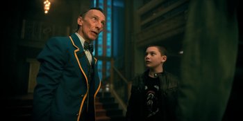 Movie still from “The Umbrella Academy” (2019), created by Steve Blackman – A man and a boy standing next to each other; Medium shot, Low angle