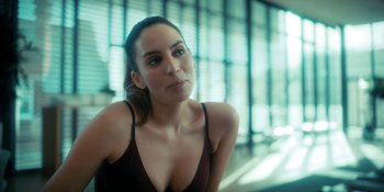 Movie still from “The Umbrella Academy” (2019), created by Steve Blackman – A woman in a black tank top is posing for a picture; Close Up shot, Over the shoulder angle