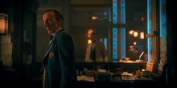 Movie still from “The Umbrella Academy” (2019), created by Steve Blackman – A man in a suit and tie standing in front of a window; Medium shot, Low angle