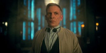 Movie still from “The Umbrella Academy” (2019), created by Steve Blackman – A man in a tan jacket and a blue shirt; Close Up shot, Low angle