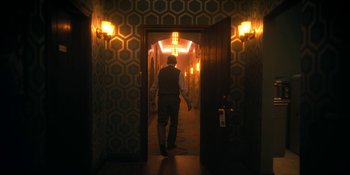 Movie still from “The Umbrella Academy” (2019), created by Steve Blackman – A man walking down a hall way in a room; Wide shot, Over the shoulder angle