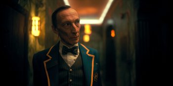 Movie still from “The Umbrella Academy” (2019), created by Steve Blackman – A man wearing a suit and bow tie in a hallway; Close Up shot, Low angle