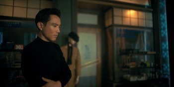 Movie still from “The Umbrella Academy” (2019), created by Steve Blackman – A man standing next to another man with his arms crossed; Medium shot, Over the shoulder angle