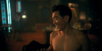 Movie still from “The Umbrella Academy” (2019), created by Steve Blackman – A man smiling while holding something in his hand; Medium shot, Over the shoulder angle