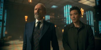 Movie still from “The Umbrella Academy” (2019), created by Steve Blackman – A man in a suit standing next to another man in a black shirt; Medium shot, Over the shoulder angle