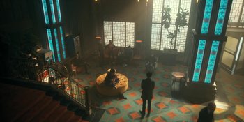 Movie still from “The Umbrella Academy” (2019), created by Steve Blackman – People are sitting in a room with a large round couch; Extreme Wide shot, High angle