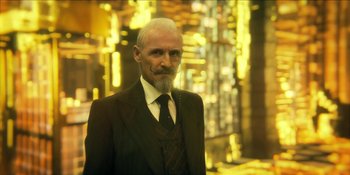 Movie still from “The Umbrella Academy” (2019), created by Steve Blackman – An older man with a beard and a suit and tie; Close Up shot, Over the shoulder angle