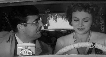 Movie still from “The Visit” (1964), directed by Bernhard Wicki – A man and a woman sitting in the driver's seat of a car; Close Up shot, Low angle