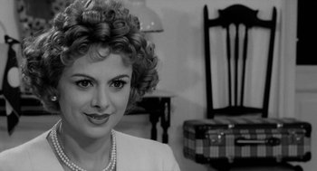 Movie still from “The Visit” (1964), directed by Bernhard Wicki – A black and white photo of a woman in a white jacket; Close Up shot, Over the shoulder angle