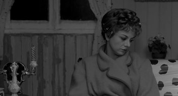Movie still from “The Visit” (1964), directed by Bernhard Wicki – A black and white photo of a woman wearing a coat; Close Up shot, High angle