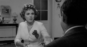 Movie still from “The Visit” (1964), directed by Bernhard Wicki – An older woman talking to a man in a room; Close Up shot, Over the shoulder angle