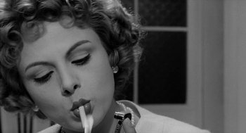 Movie still from “The Visit” (1964), directed by Bernhard Wicki – A black and white photo of a woman holding a razor; Close Up shot, Low angle
