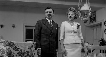 Movie still from “The Visit” (1964), directed by Bernhard Wicki – An older man and woman standing next to each other; Medium shot, Low angle