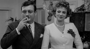 Movie still from “The Visit” (1964), directed by Bernhard Wicki – An older man smoking a cigarette next to an older woman; Close Up shot, Low angle